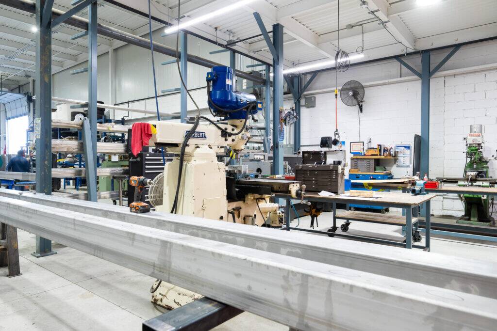 "Metal fabrication workshop at ATH Custom Metal Fabrication with machinery and long metal parts."