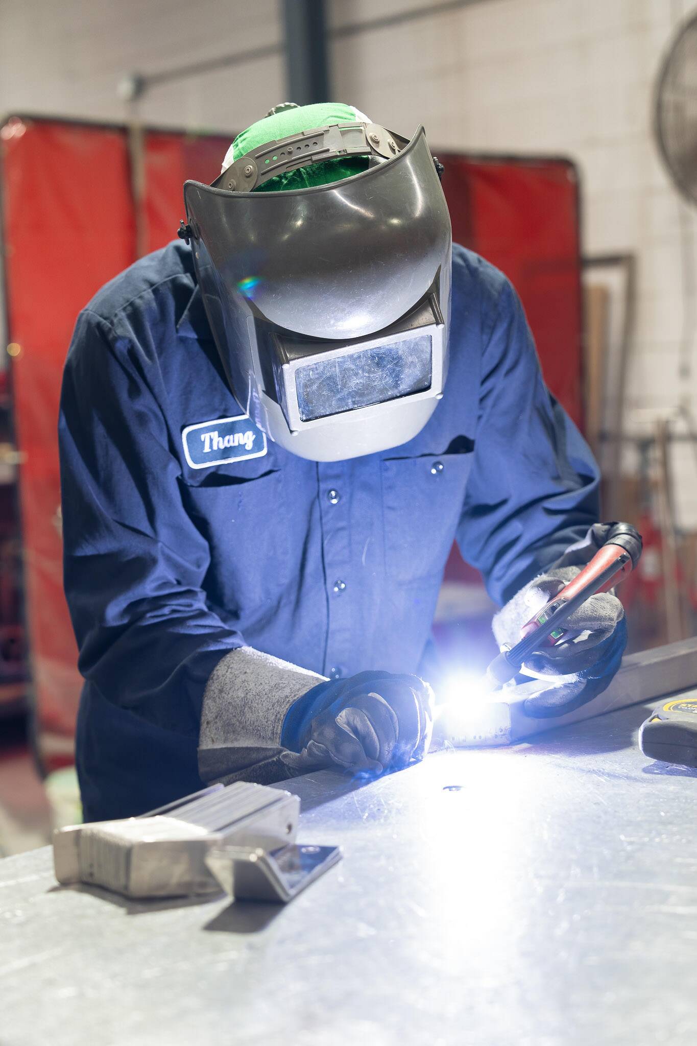 "ATH Custom Metal Fabrication worker welding metal with protective gear."