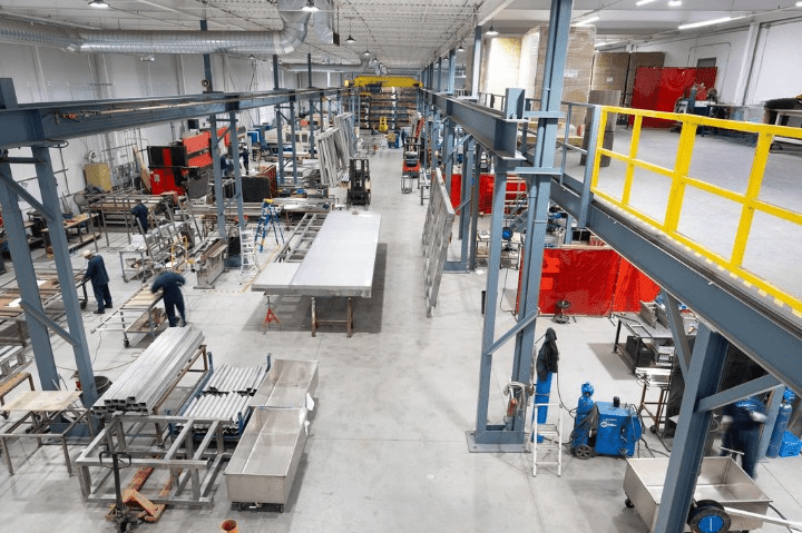 "Busy interior of the ATH Custom Metal Fabrication workshop with workers and machinery"